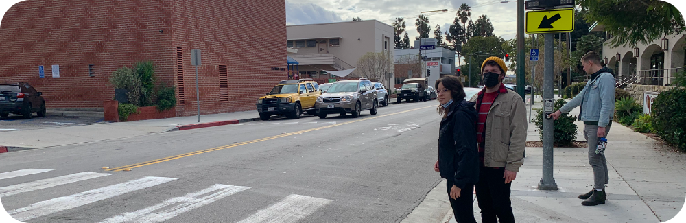 Pedestrians wait to cross the street at a crosswalk