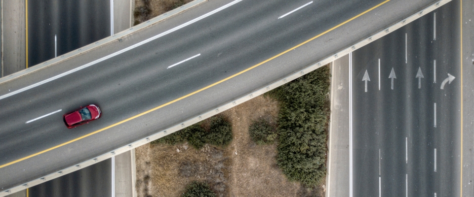A red car travels along a highway