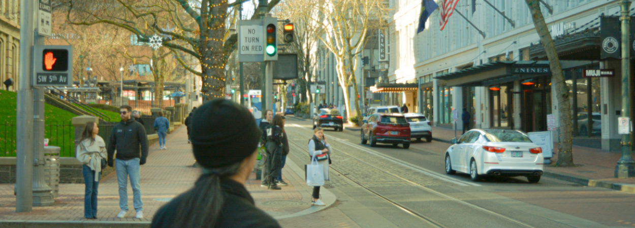 People waiting at a crosswalk intersection outside of Pioneer Place in Portland, Oregon.