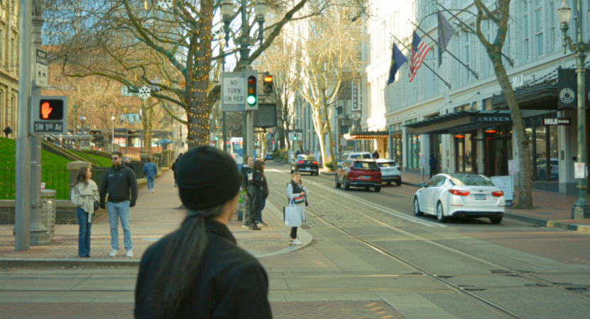 People waiting at a crosswalk intersection outside of Pioneer Place in Portland, Oregon.